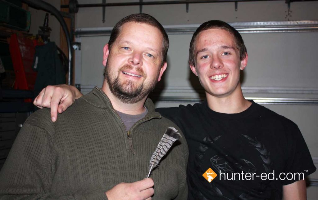 Hunter education instructor Randy Allen with his son and the grouse feather they received as a gift.