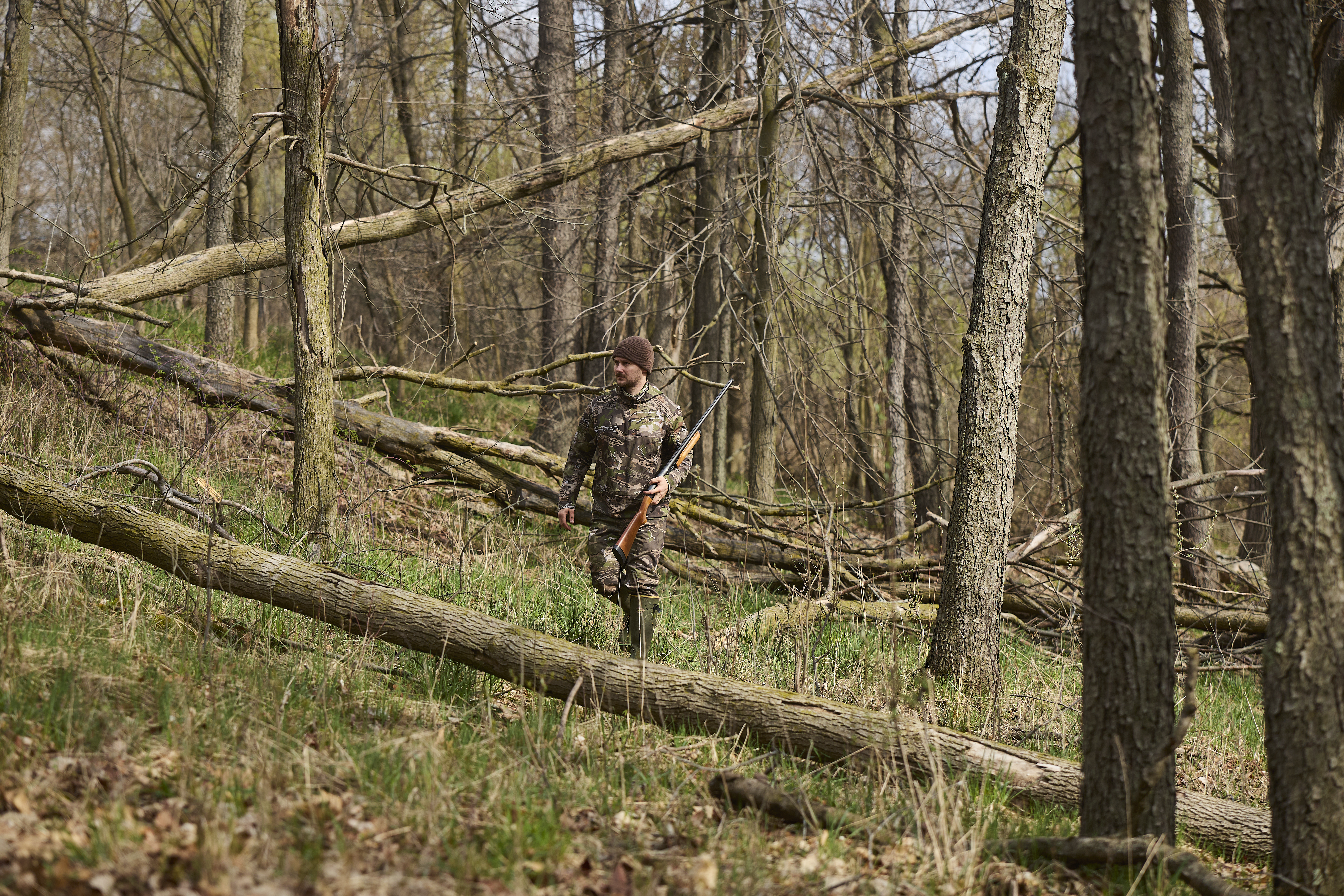 A hunter walking in the woods with a firearm, safety with a hunting knife concept. 
