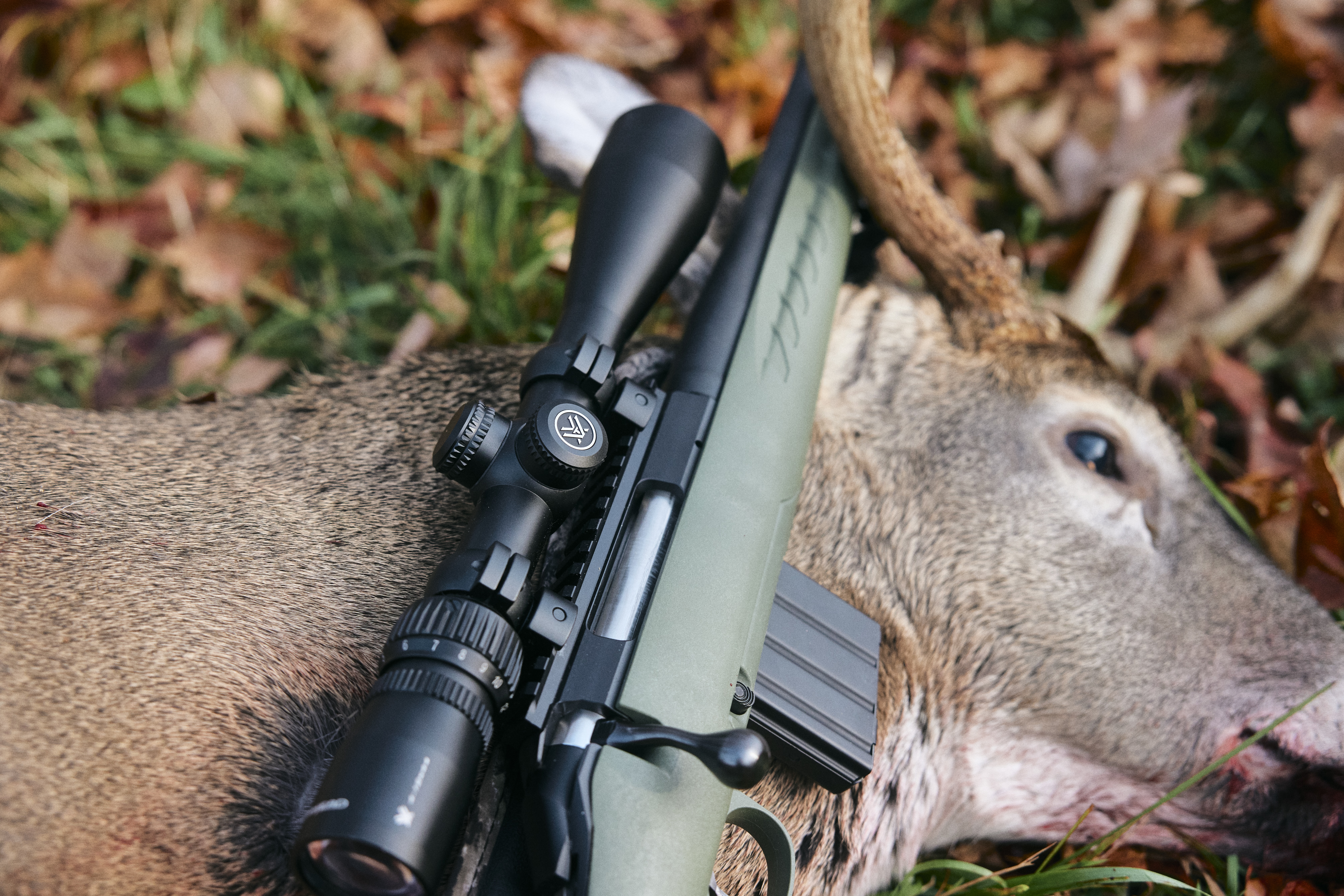 A hunters firearm on a deer after a kill shot. 