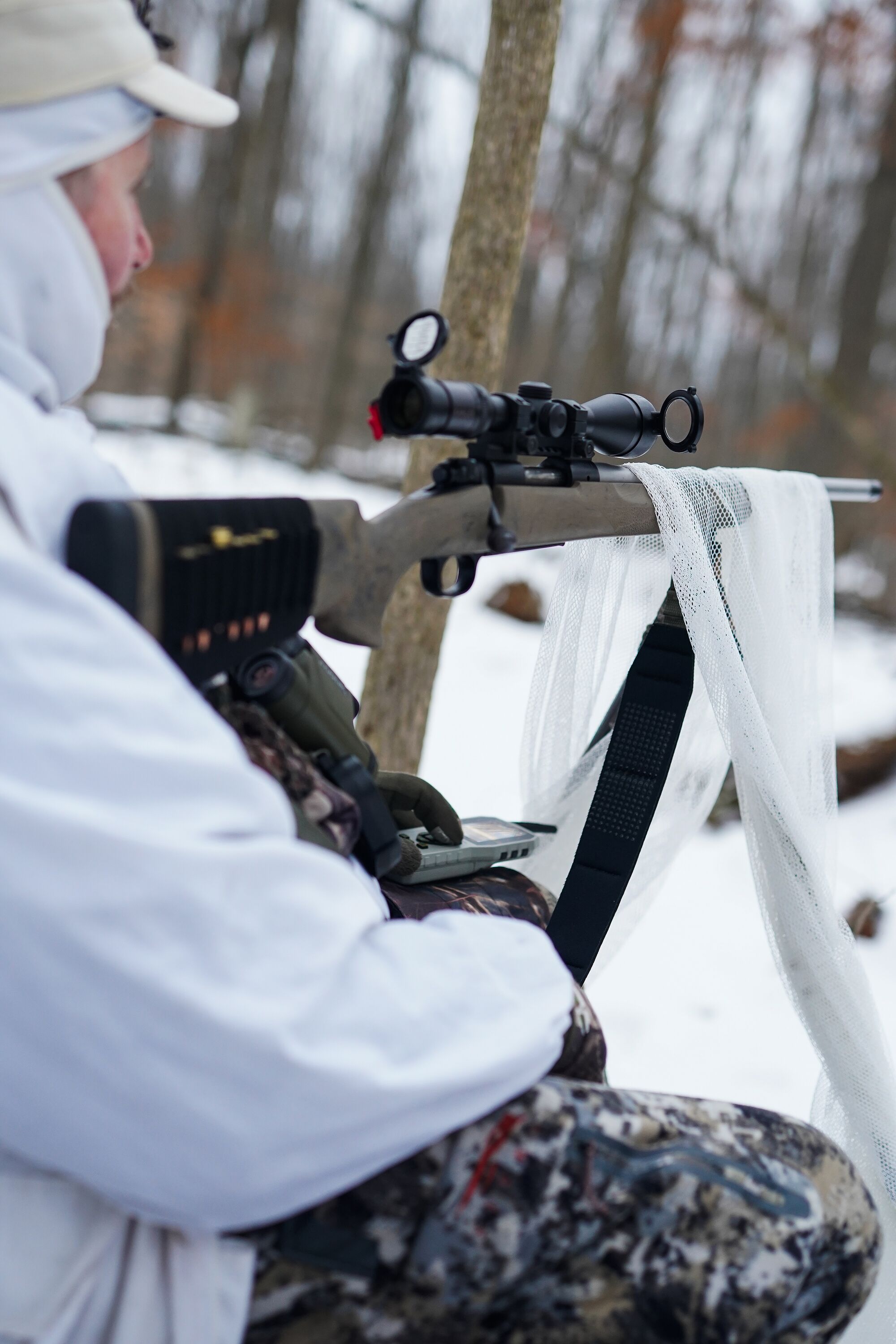 A hunter set up for hunting coyotes with a rifle, scope, and stand. 