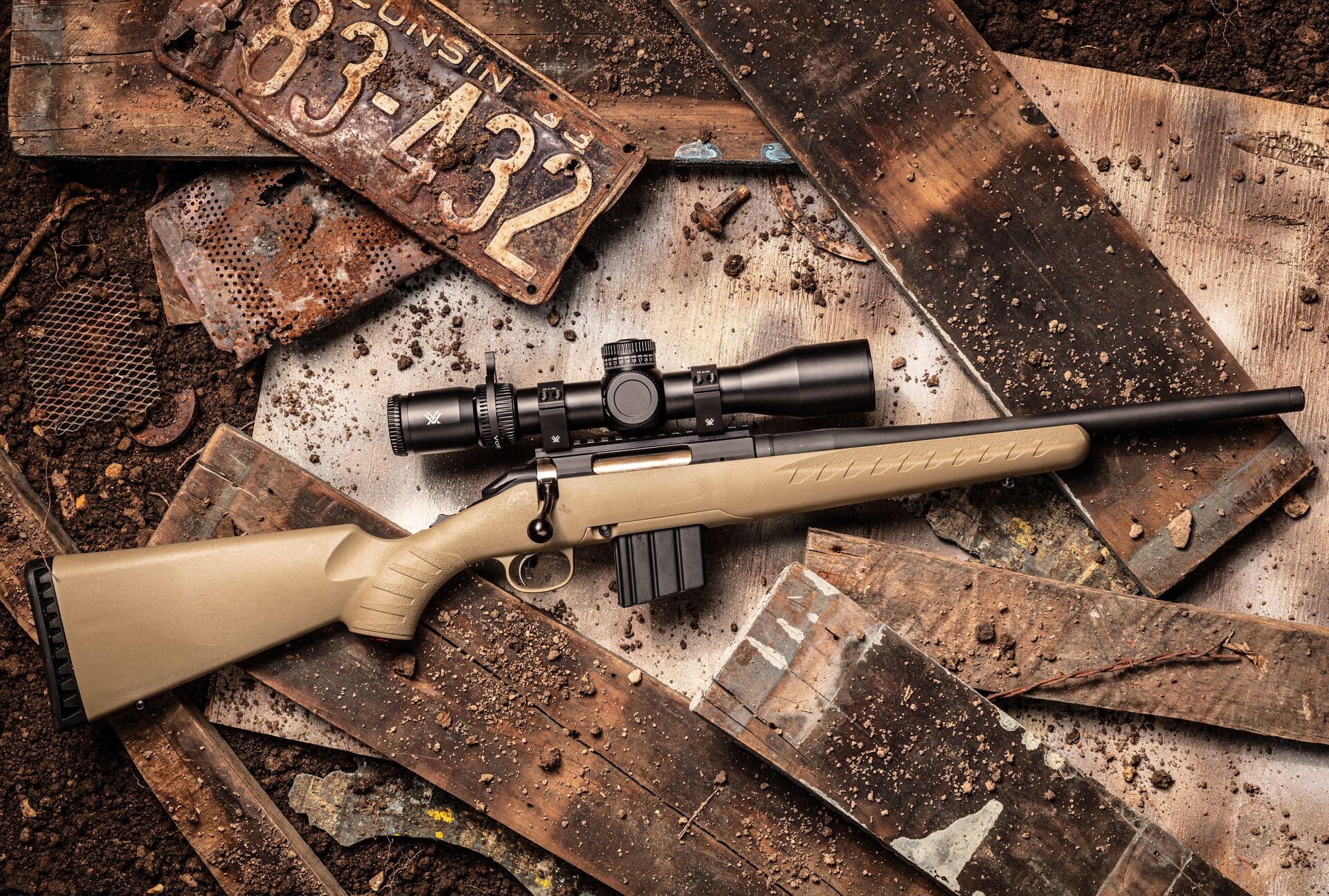 A hunting rifle with a scope on its side on a table.