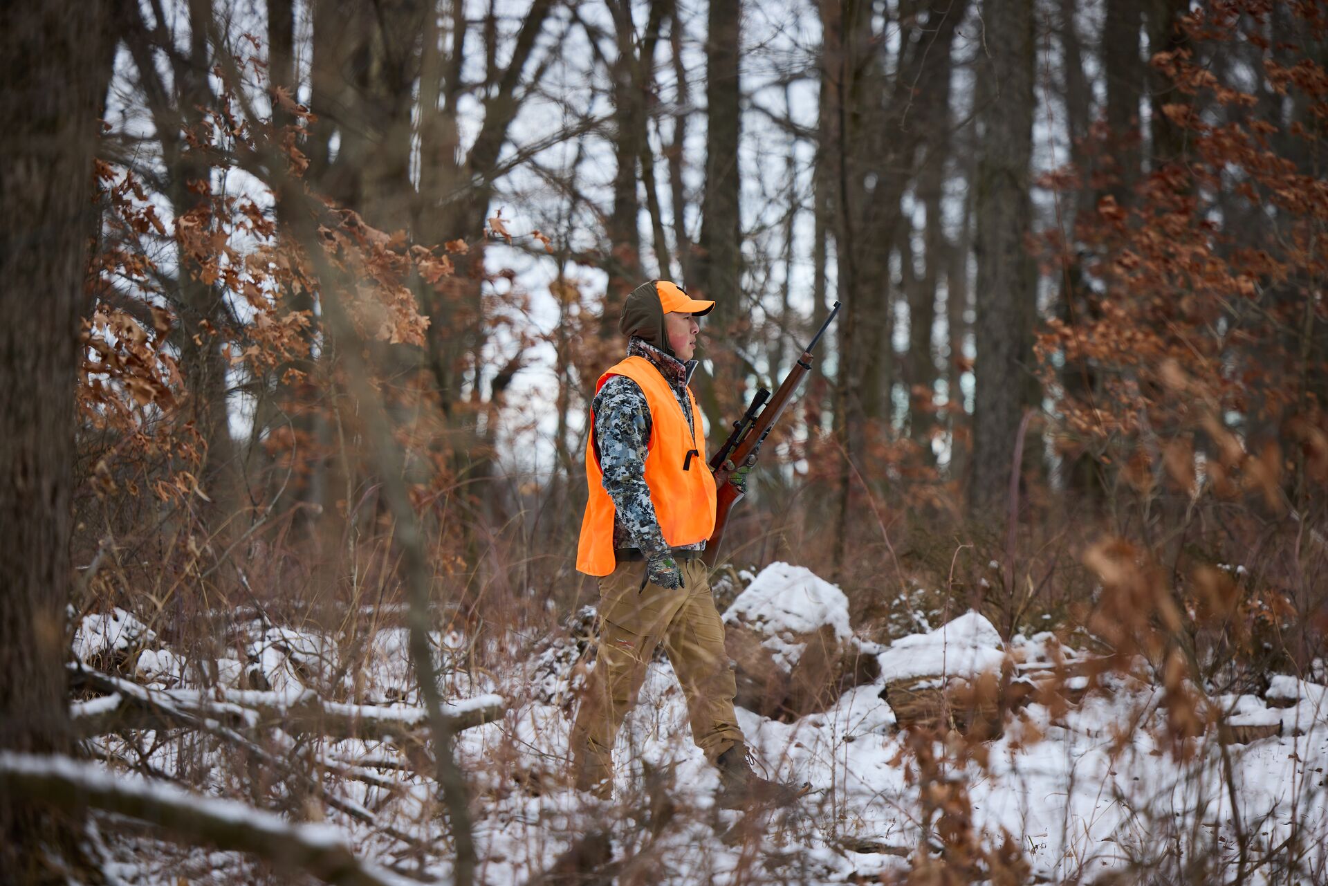 A hunter in blaze orange in the snowy woods, get a New Jersey hunting license concept. 