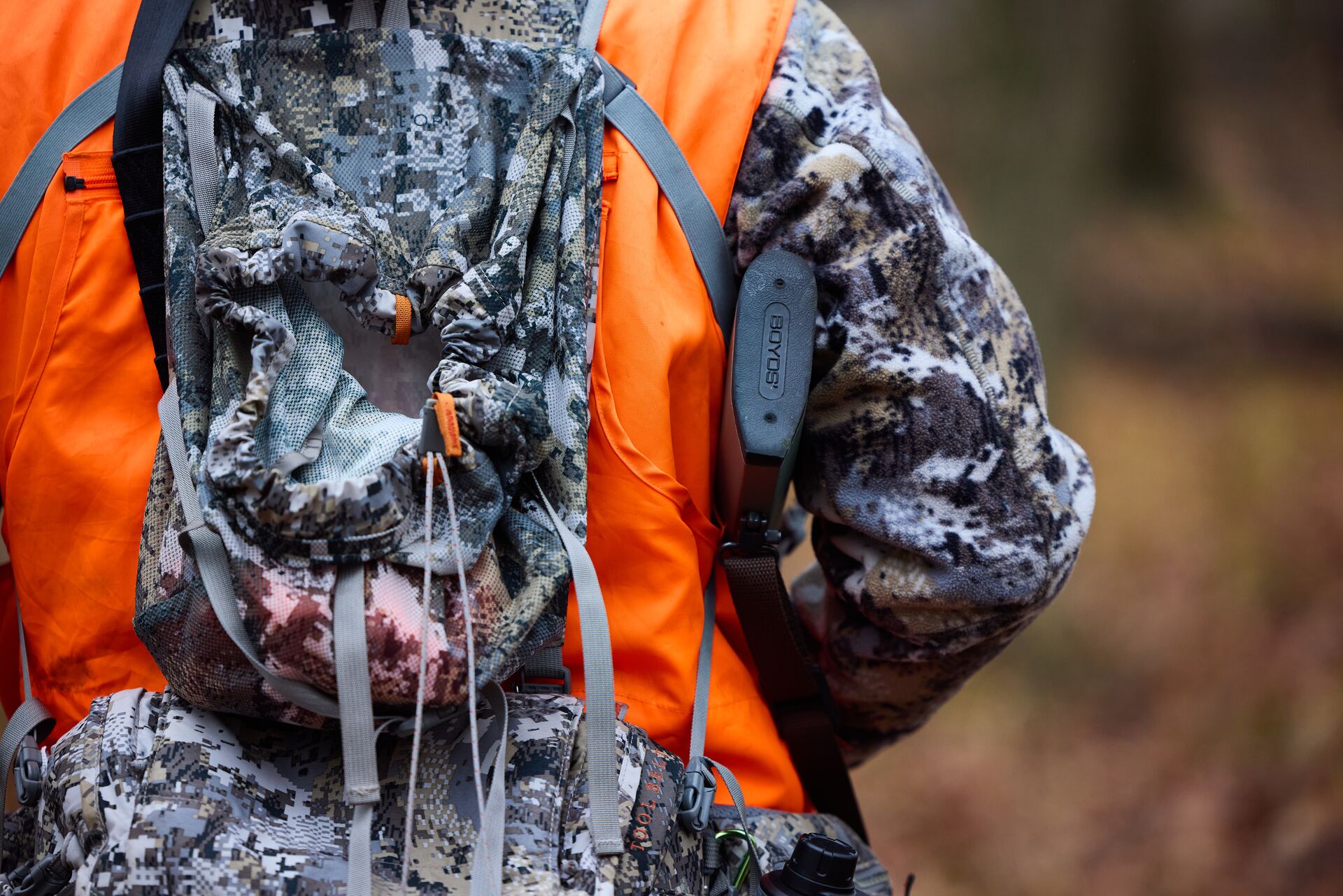 Close-up of the back of a hunter in camo and blaze orange, hunting for beginners concept. 