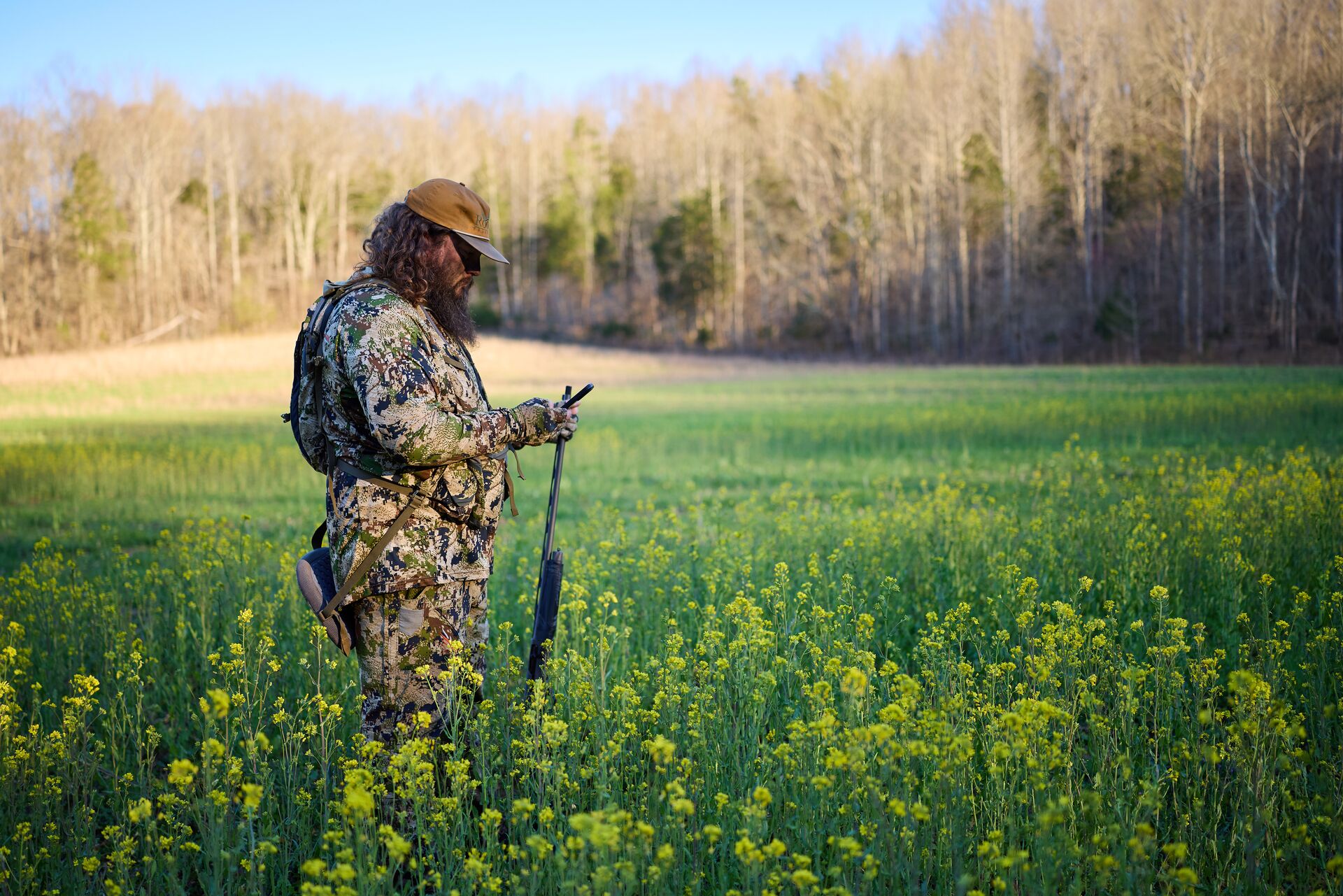 Hunter in a field using an app to find where to hunt. 