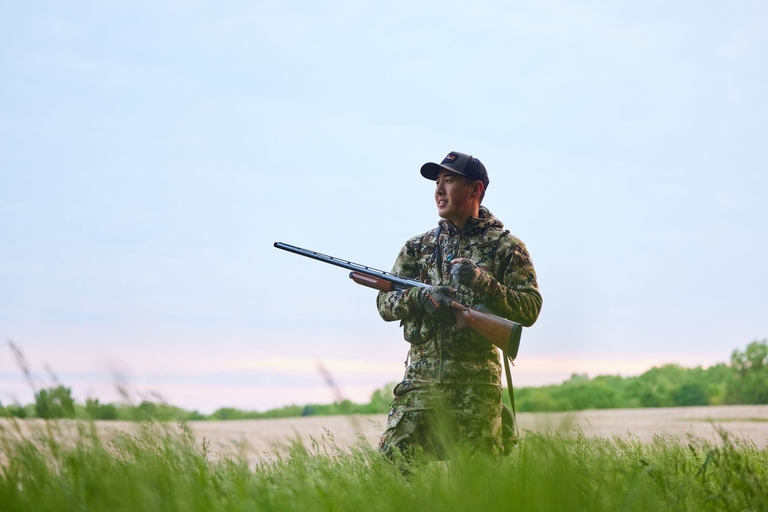 Smiling hunter in camo with shotgun, how to get into hunting concept. 