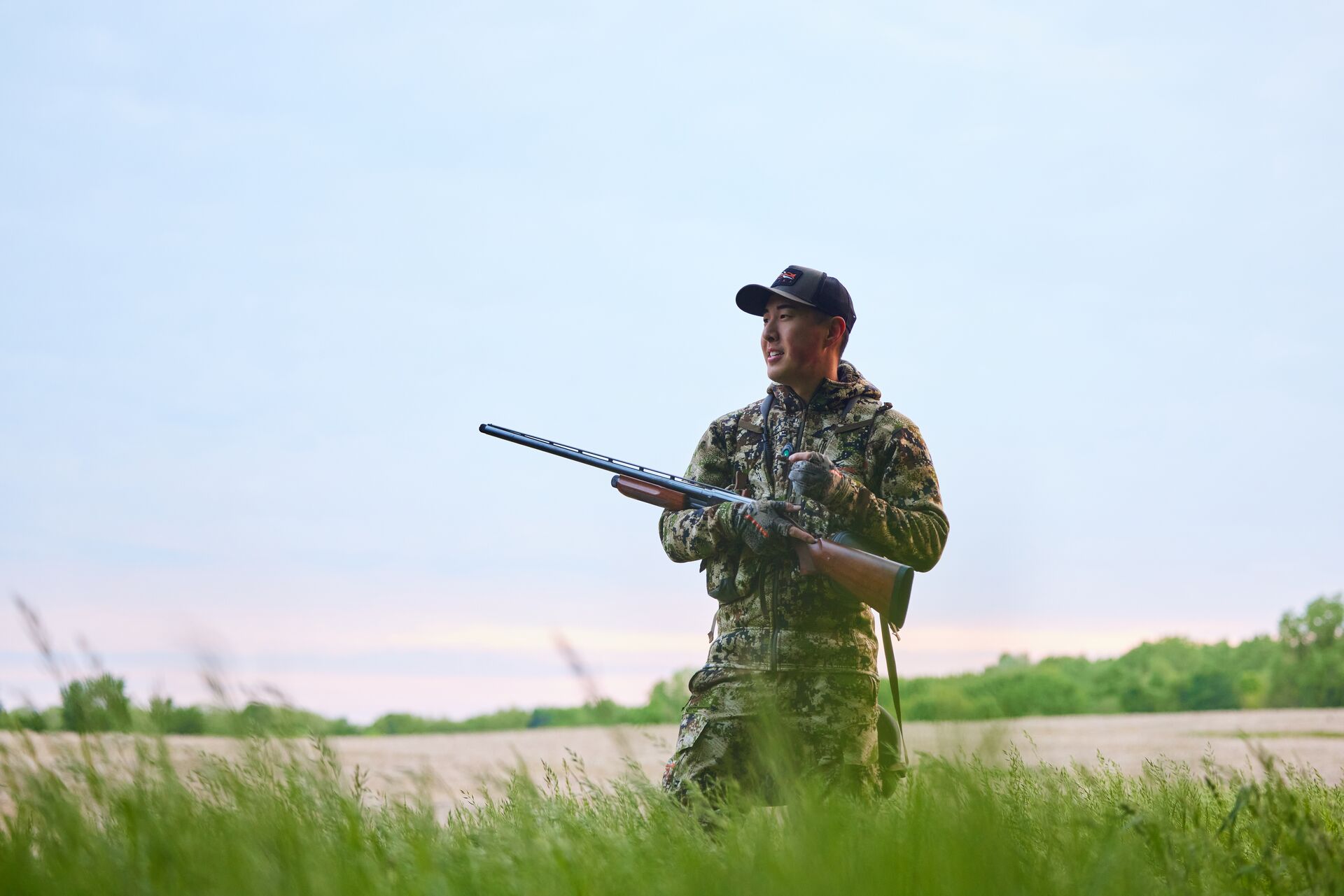 Smiling hunter in camo with shotgun, how to get into hunting concept. 