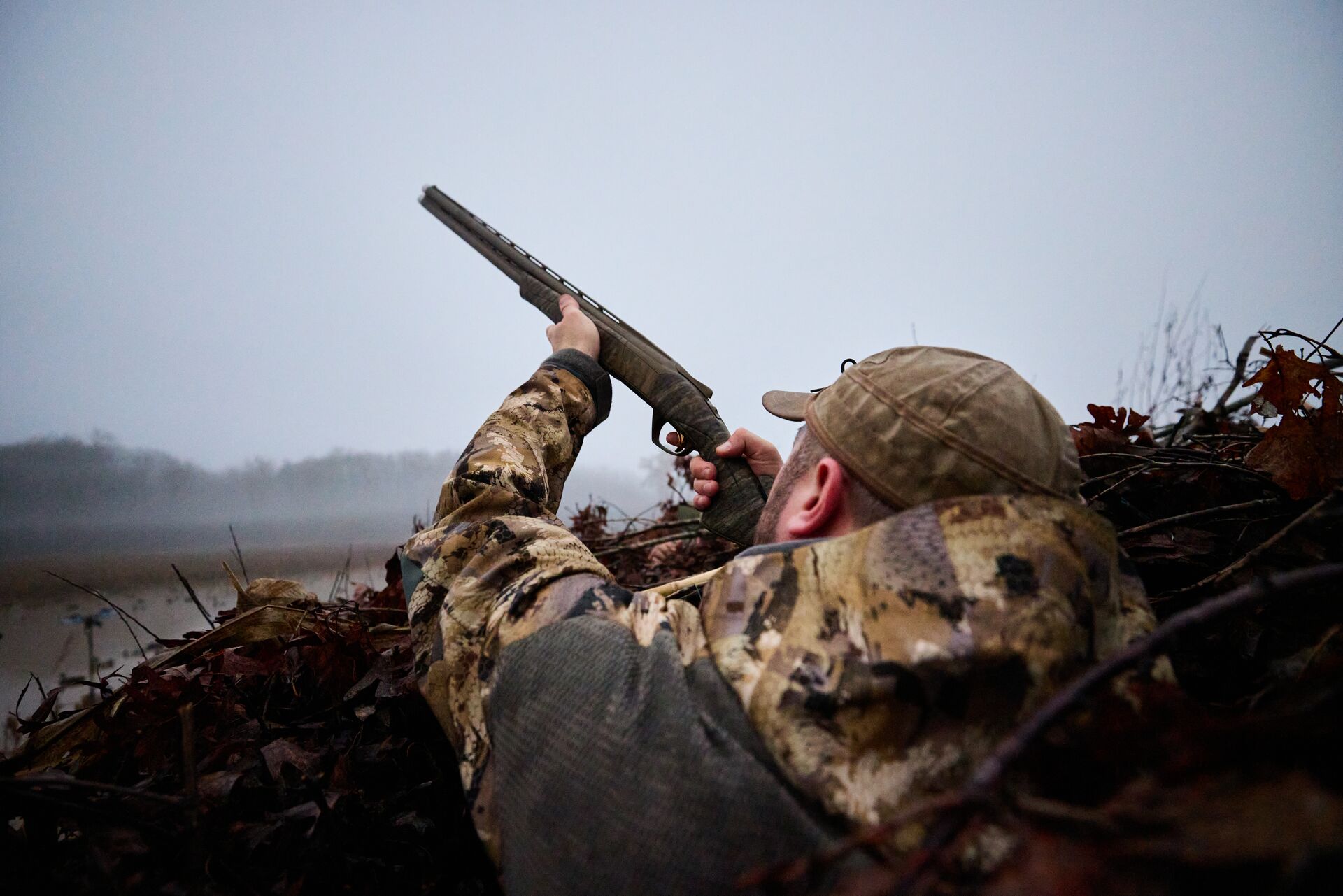 Hunter in duck blind aims shotgun, NC waterfowl season concept. 