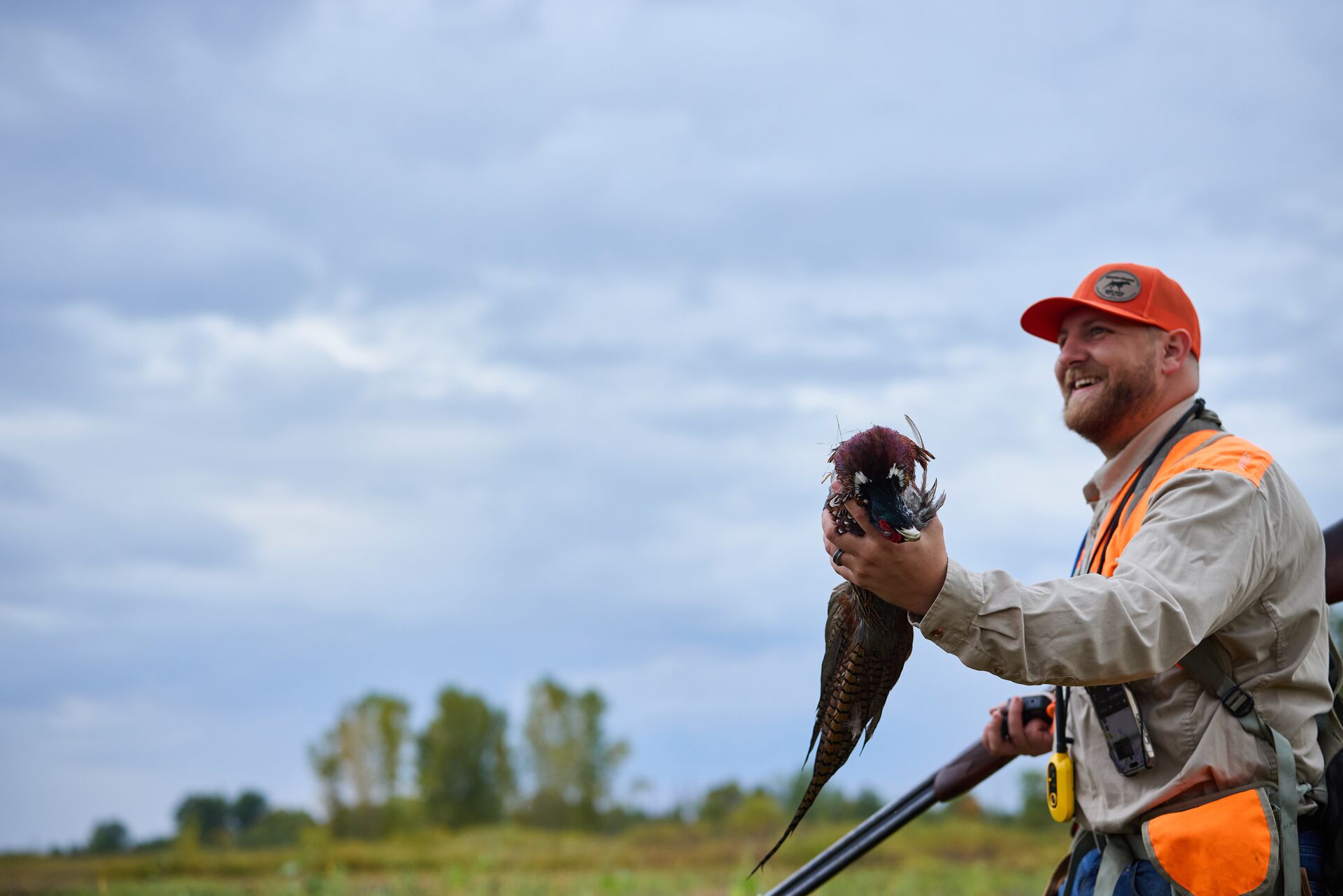 Smiling hunter holds pheasant during hunt, pheasant season Montana concept. 