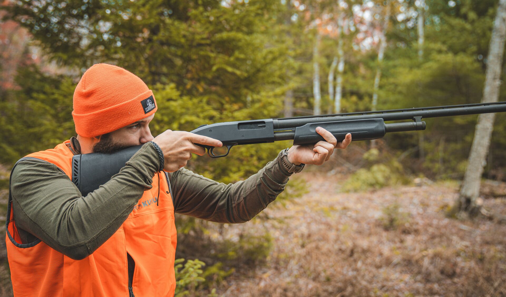 Hunter in blaze orange aims a shotgun, how to get a New Jersey hunting license concept.