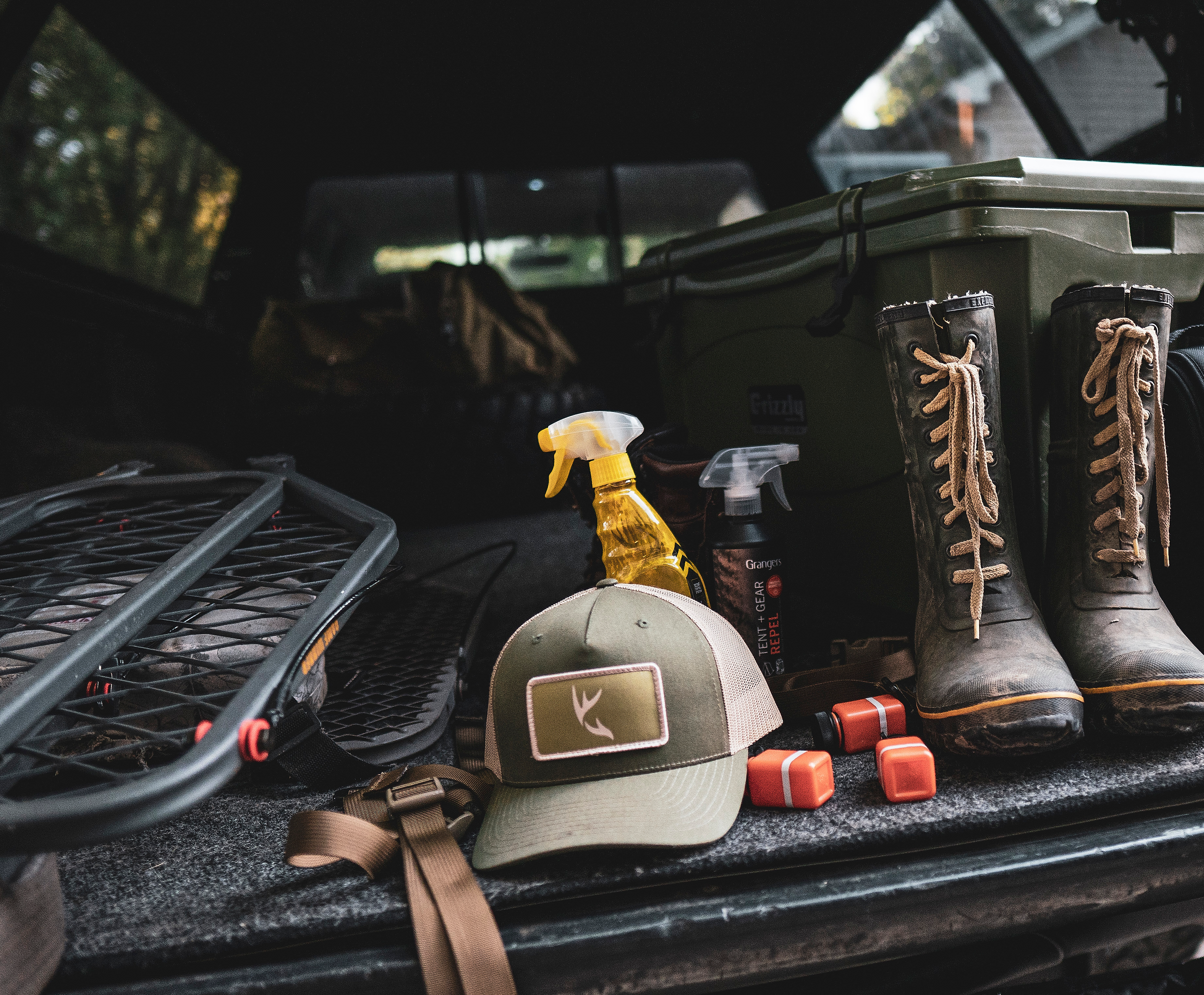 Hat, tree stand, boots, and other hunting gear in back of truck, beginner hunting checklist concept.