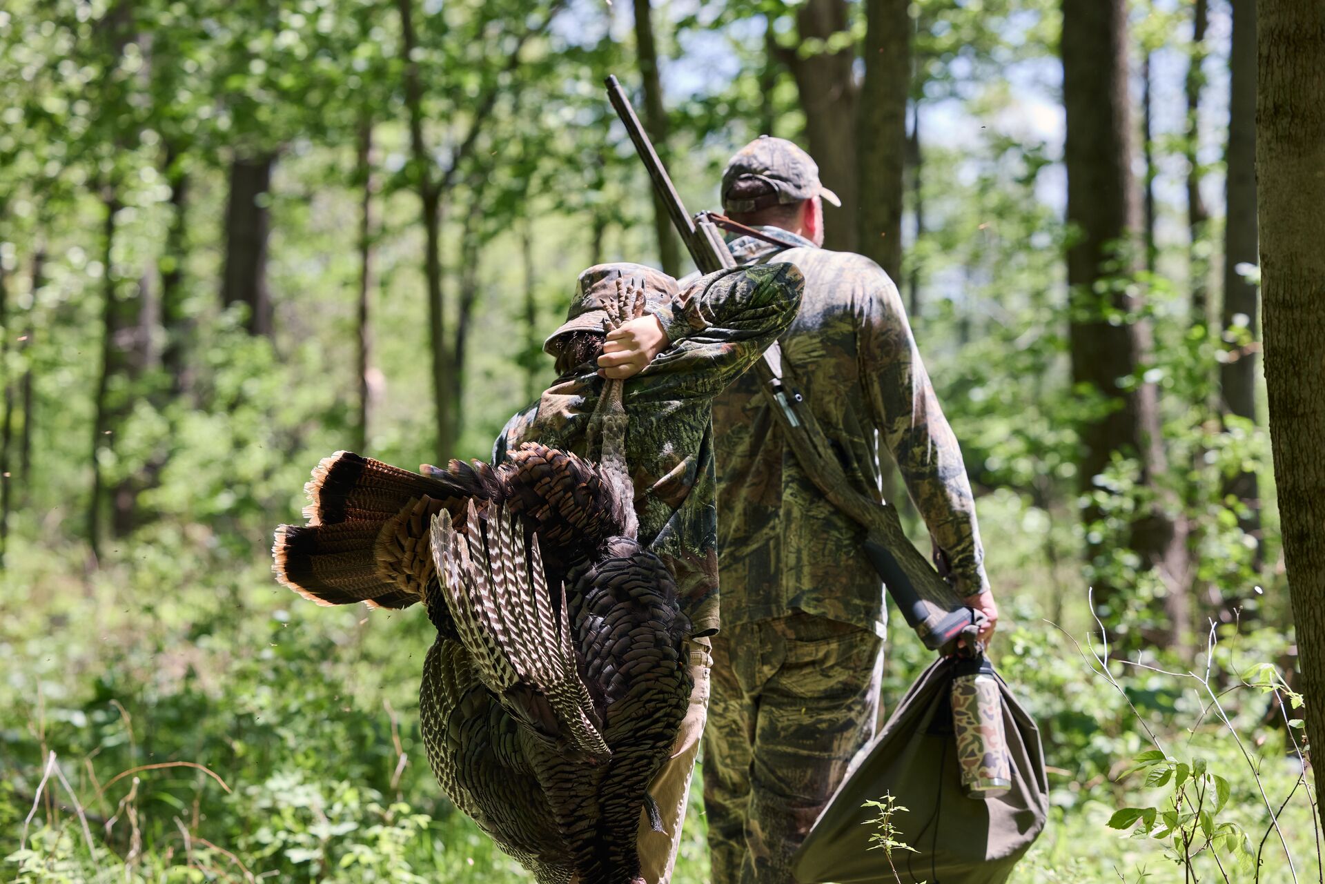 Boy and man in camo with turkey after hunt, represents turkey hunting for beginners.