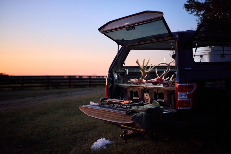 Hunting gear and deer antlers in back of truck, understand hunting regulations concept.
