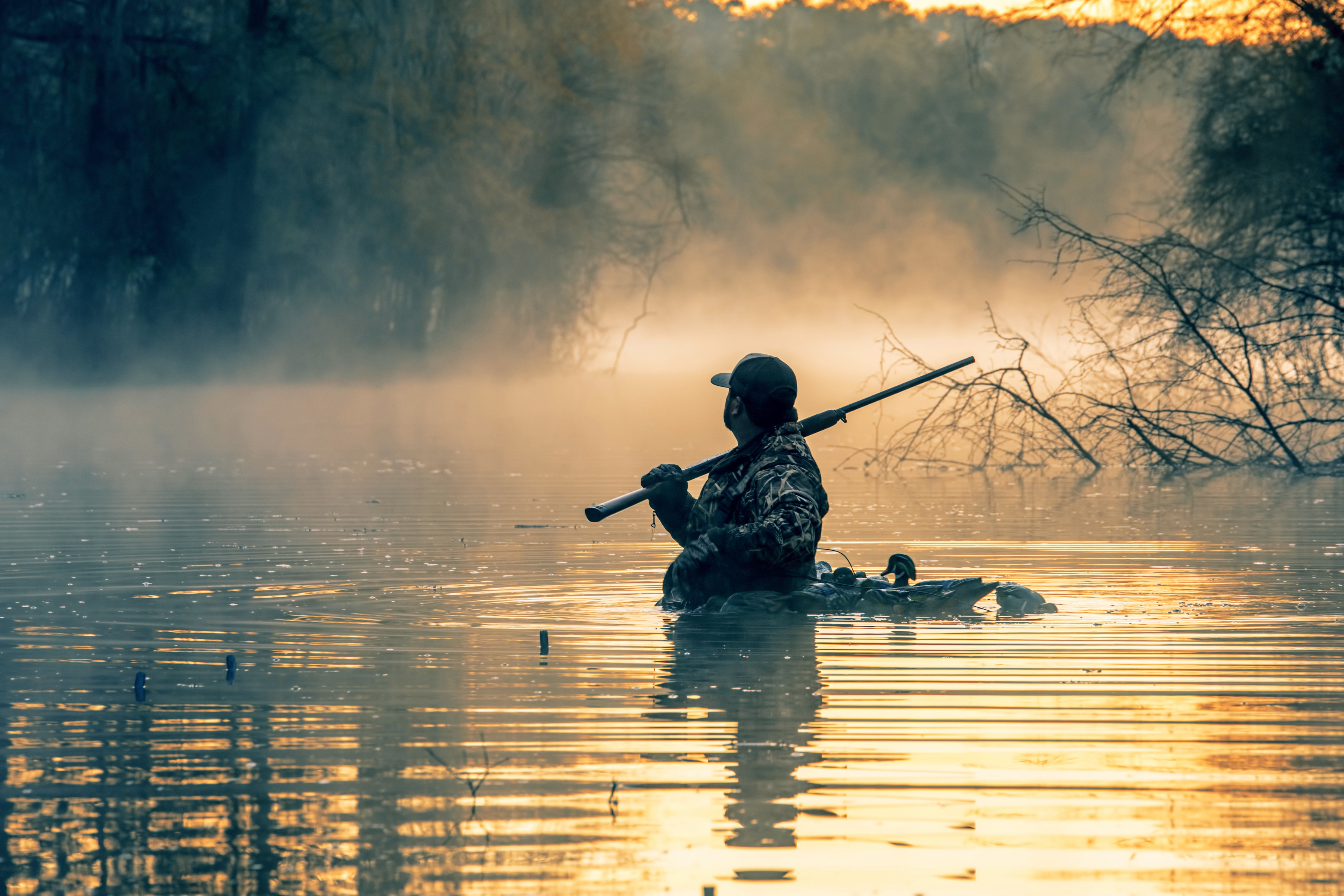 A waterfowl hunter in the water, firearm safety rules Hunter-Ed concept. 