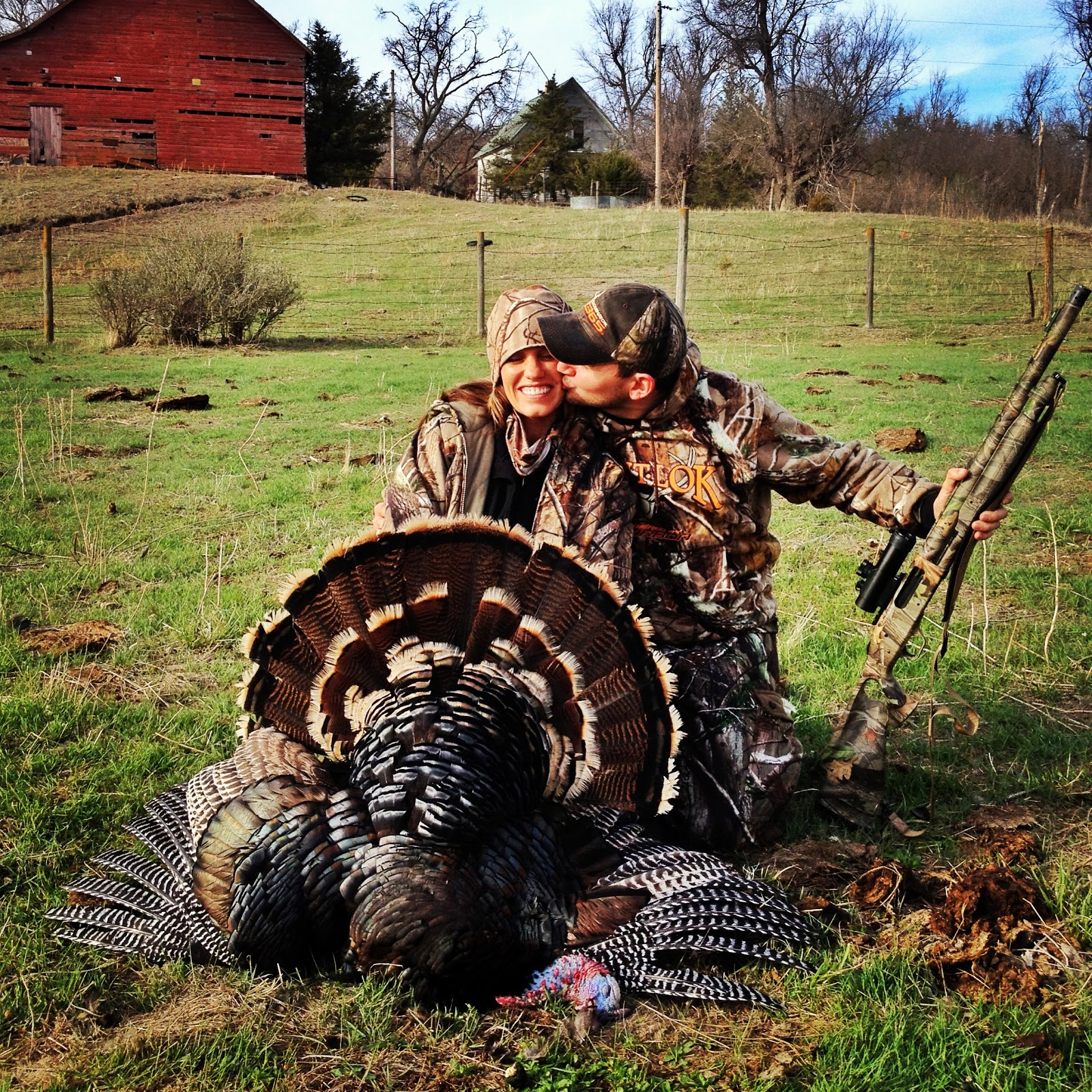 A man kisses a woman next to a turkey they hunted, how to hunt safely. 