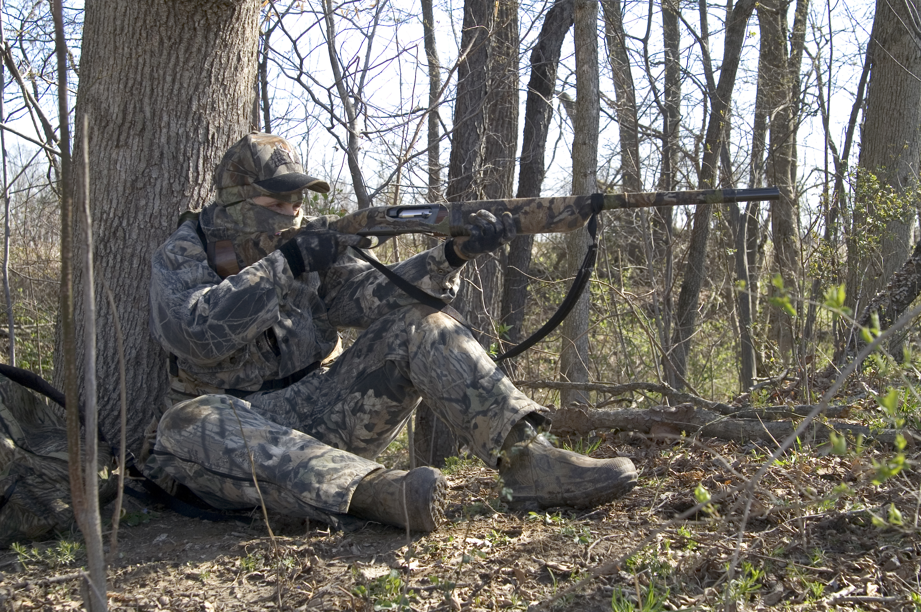 A hunter aims a firearm at a target, taking a hunter safety course concept. 