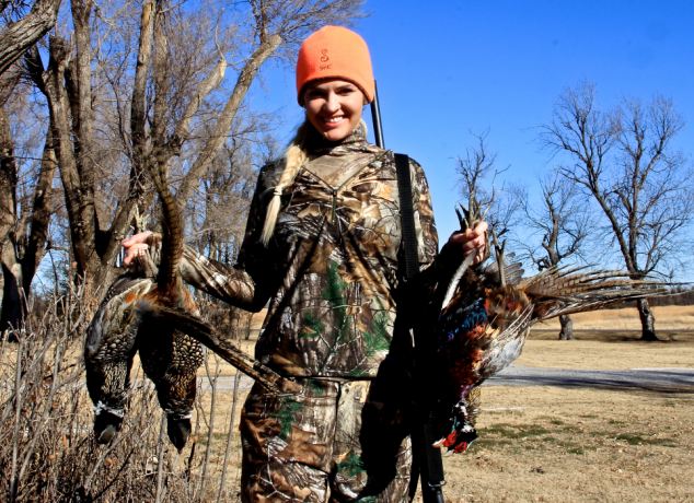 Theresa Vail in hunting clothing holding harvested birds. 
